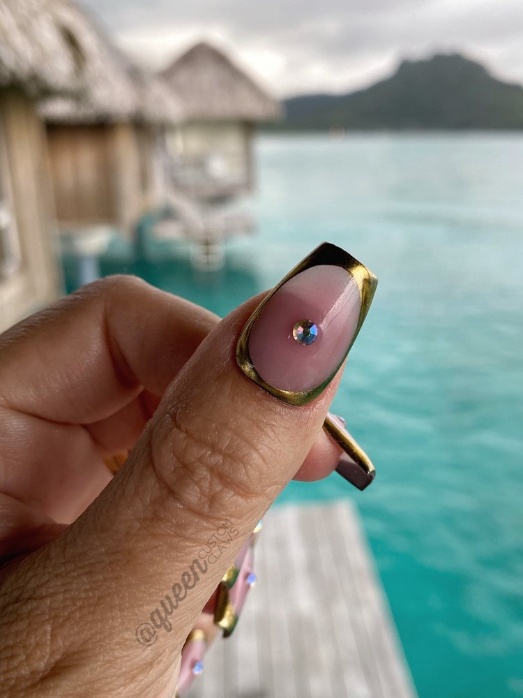 picture of a hand and nails showing custom handmade gel nail designs.  this design features a Natural shimmer base and subtle blush aura heart encased in a chrome bezel. You can choose with or without gems