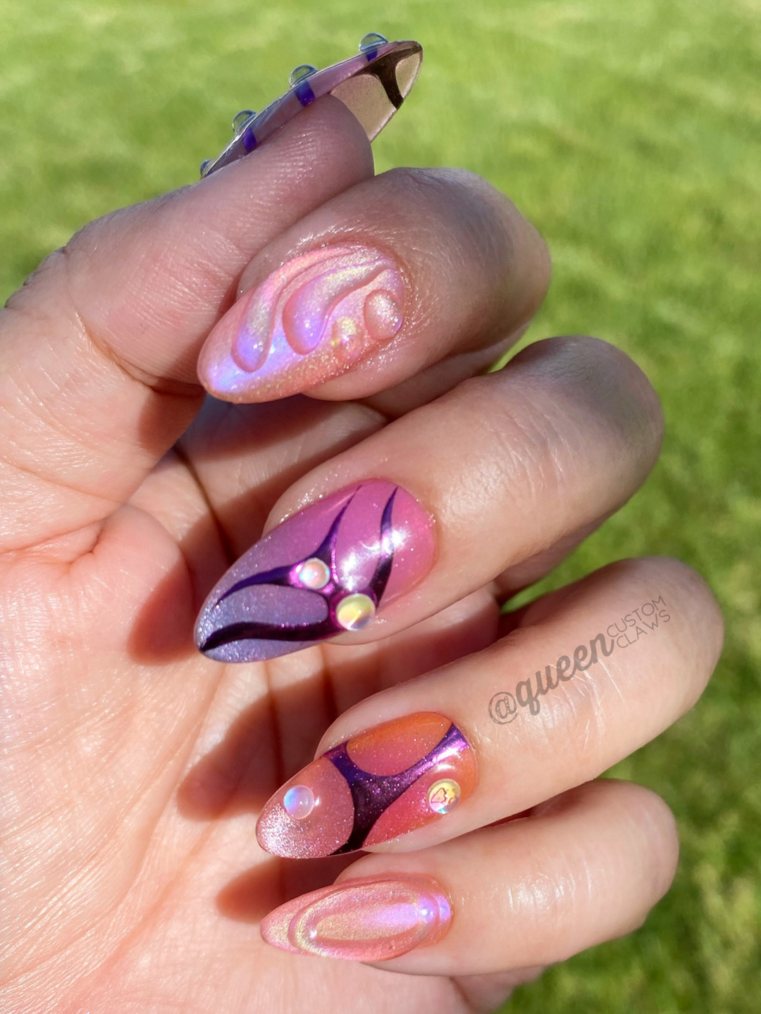 almond shaped press on nails, custom designed with chrome & ombre, with chrome tribal swirls, 3d gem dots & jelly swoop accents. shown in natural light, modeled on the hand
