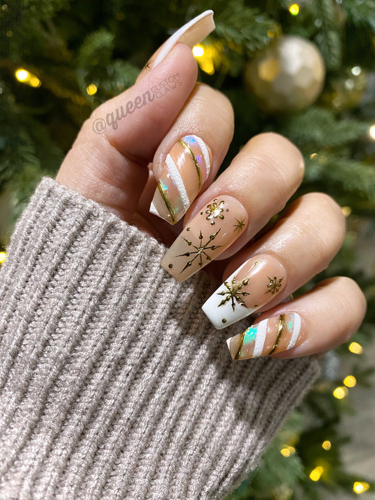 a woman's hand with a white and gold manicure showing a Christmas themed nail design. press on nail manicure